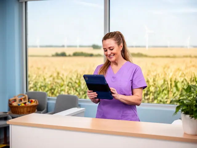 Smiling office manager in lavender scrubs reviewing a navy tablet at a pediatric dental front desk